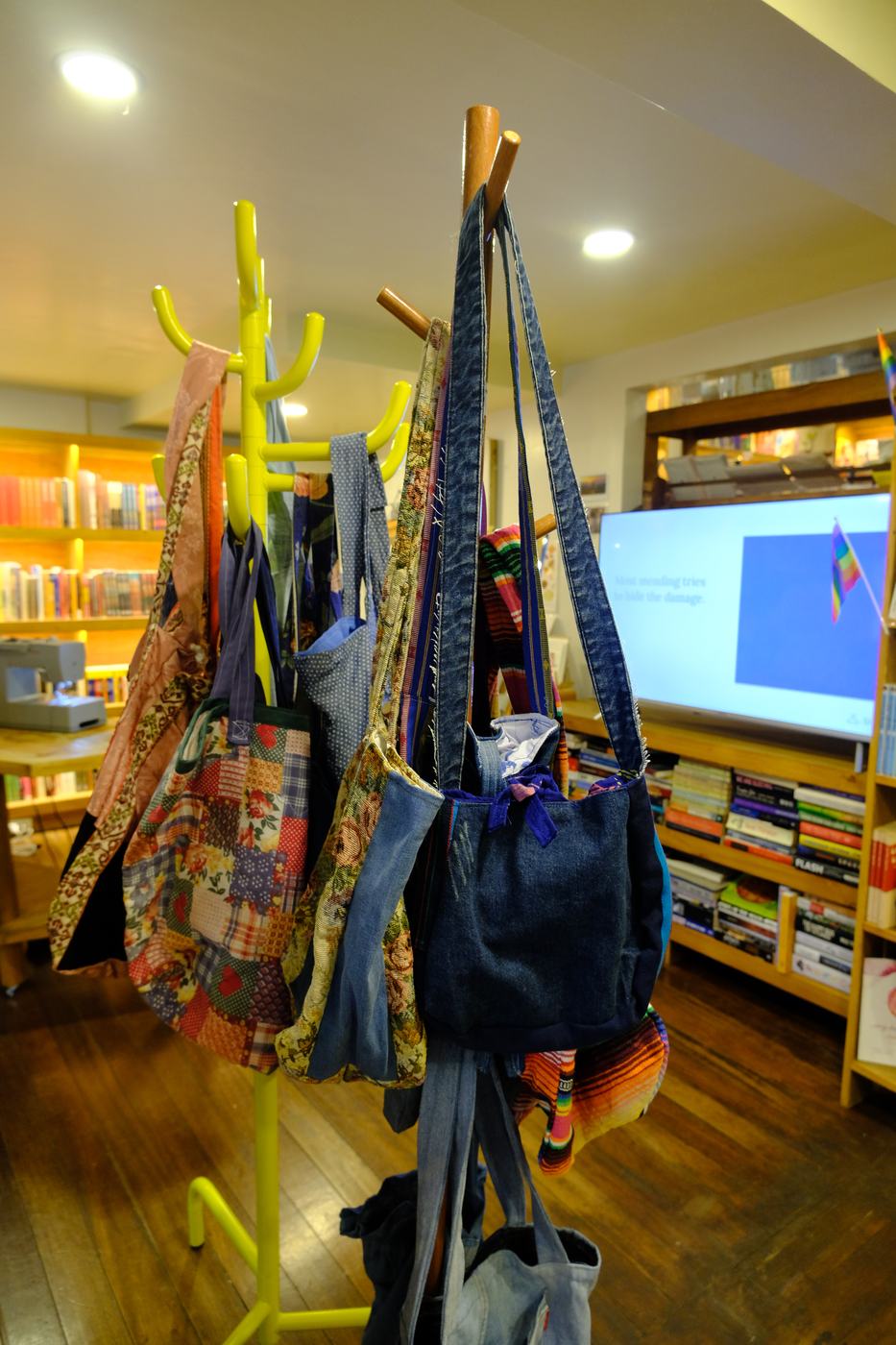 Upcycled tote bags hanging on a stand
