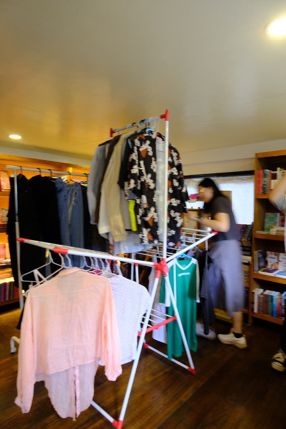 Clothes hung on racks between bookshelves